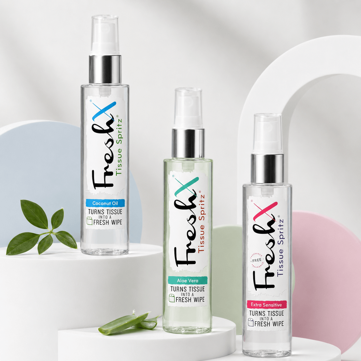 Three bottles of FreshX Tissue Spritz on a white background with a plant leaf and aloe vera.