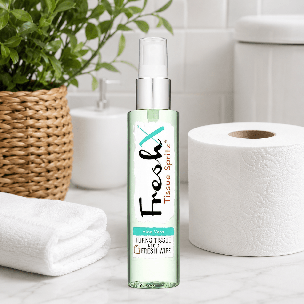 Bottle of FreshX Tissue Spritz on a bathroom counter with toilet roll and a plant in the background.