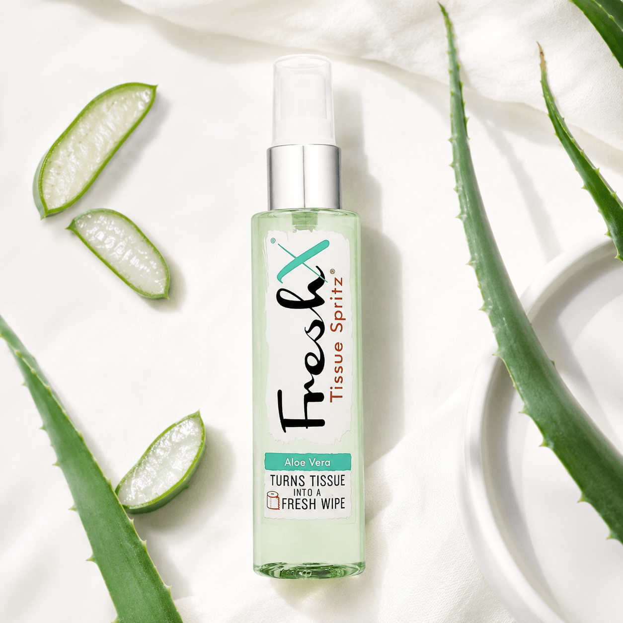 Bottle of FreshX Tissue Spritz with aloe vera leaves on a white background