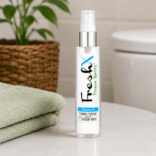FreshX Tissue Spritz bottle on a bathroom counter with tissues and a plant in the background