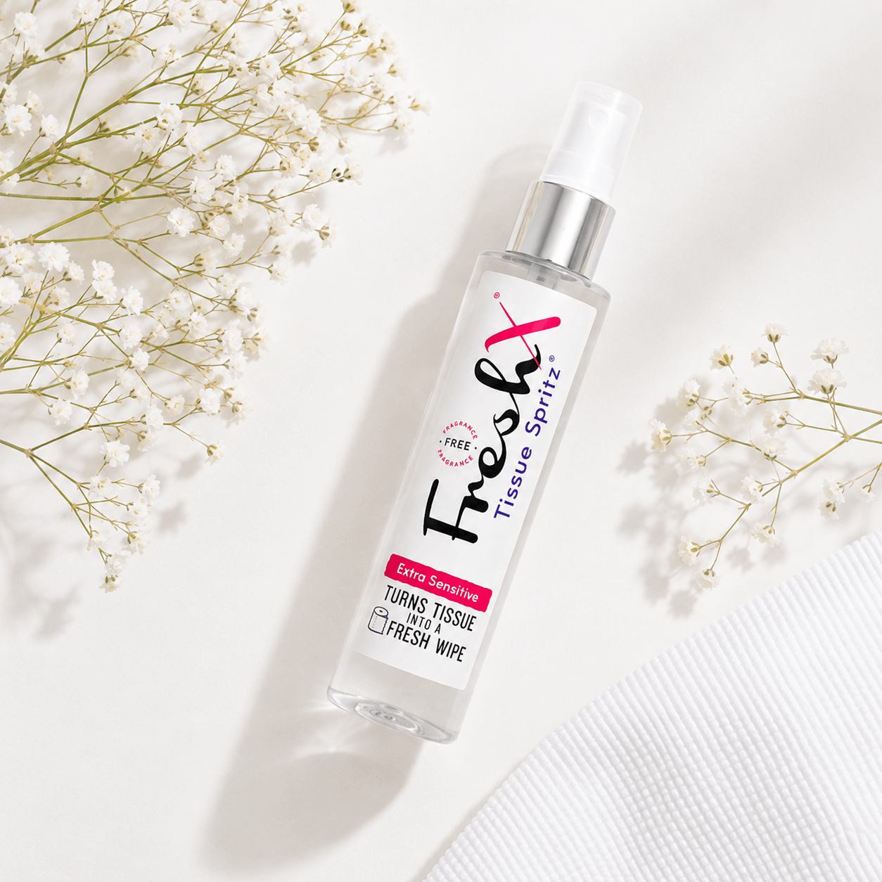 Bottle of FreshX Tissue Spritz with flowers on a light background