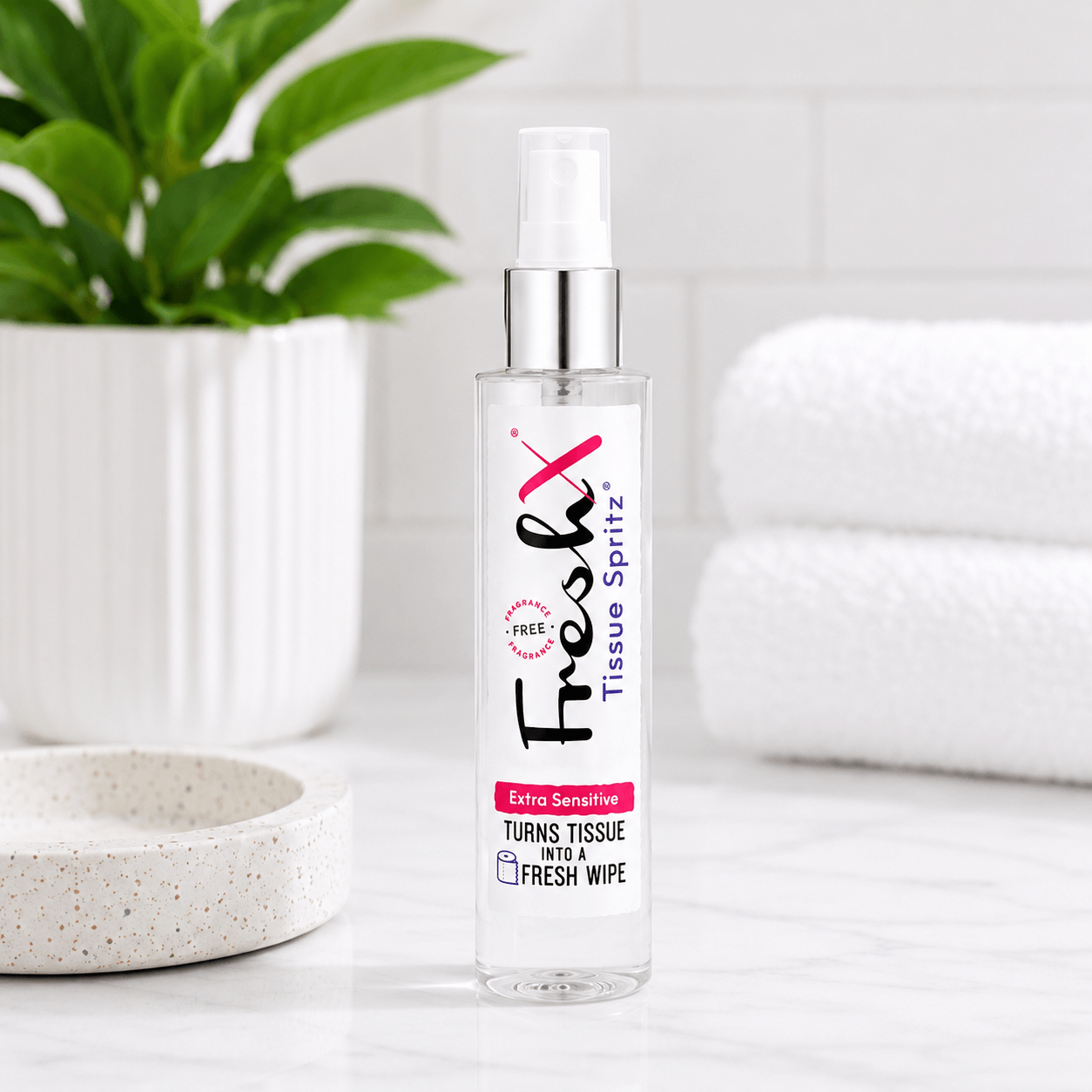 FreshX Tissue Spritz bottle on a white surface with a plant and towel in the background