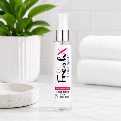 FreshX Tissue Spritz bottle on a white surface with a plant and towel in the background